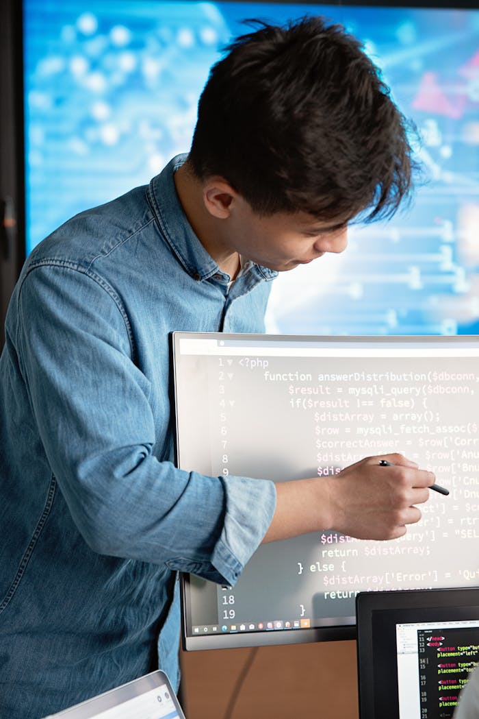 why-choose-us Asian male programmer writing code on a computer monitor in an office setting.
